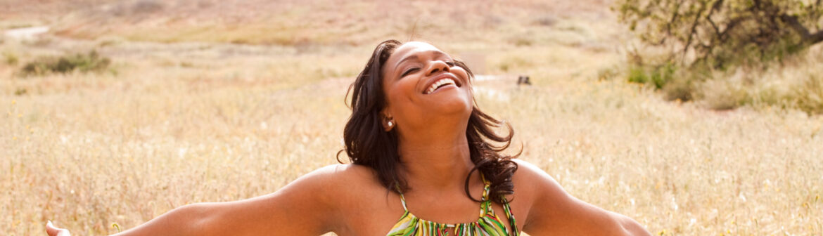 A woman in a field with her arms outstretched.