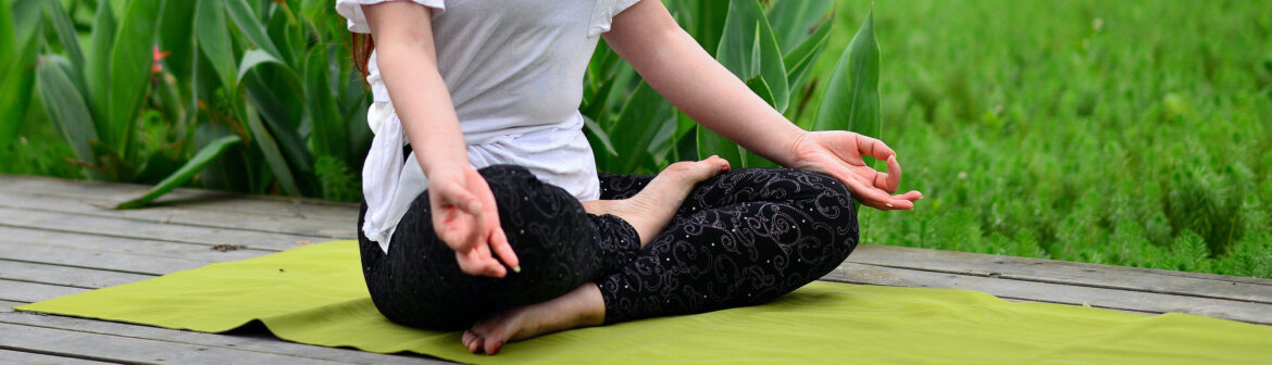 A woman sitting on the ground in a yoga pose.